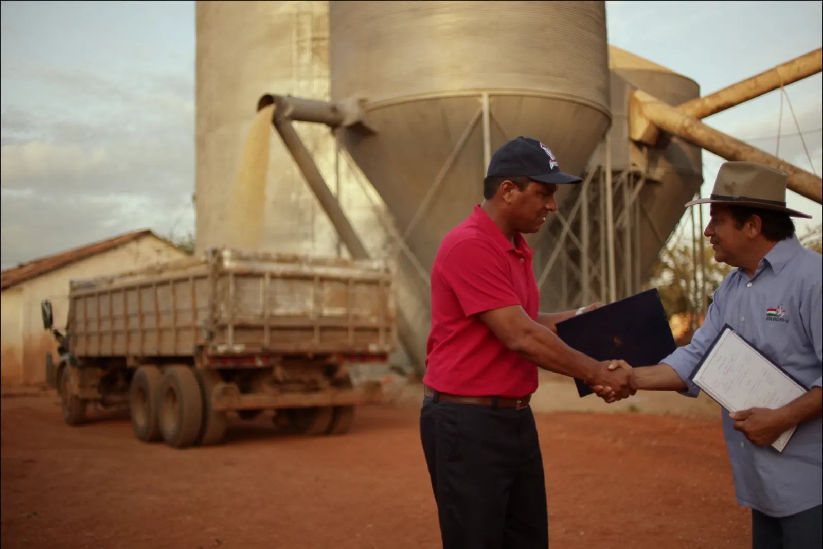 Comprador y vendedor se dan la mano mientras se carga el camión en el silo