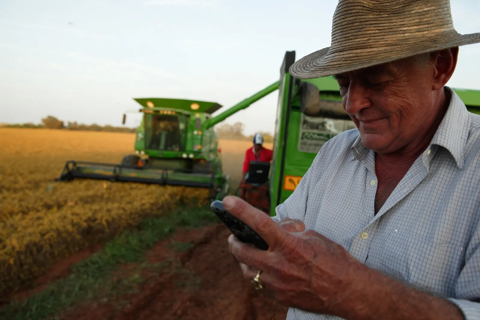 Productor siguiendo las ofertas en el celular durante la cosecha de soja